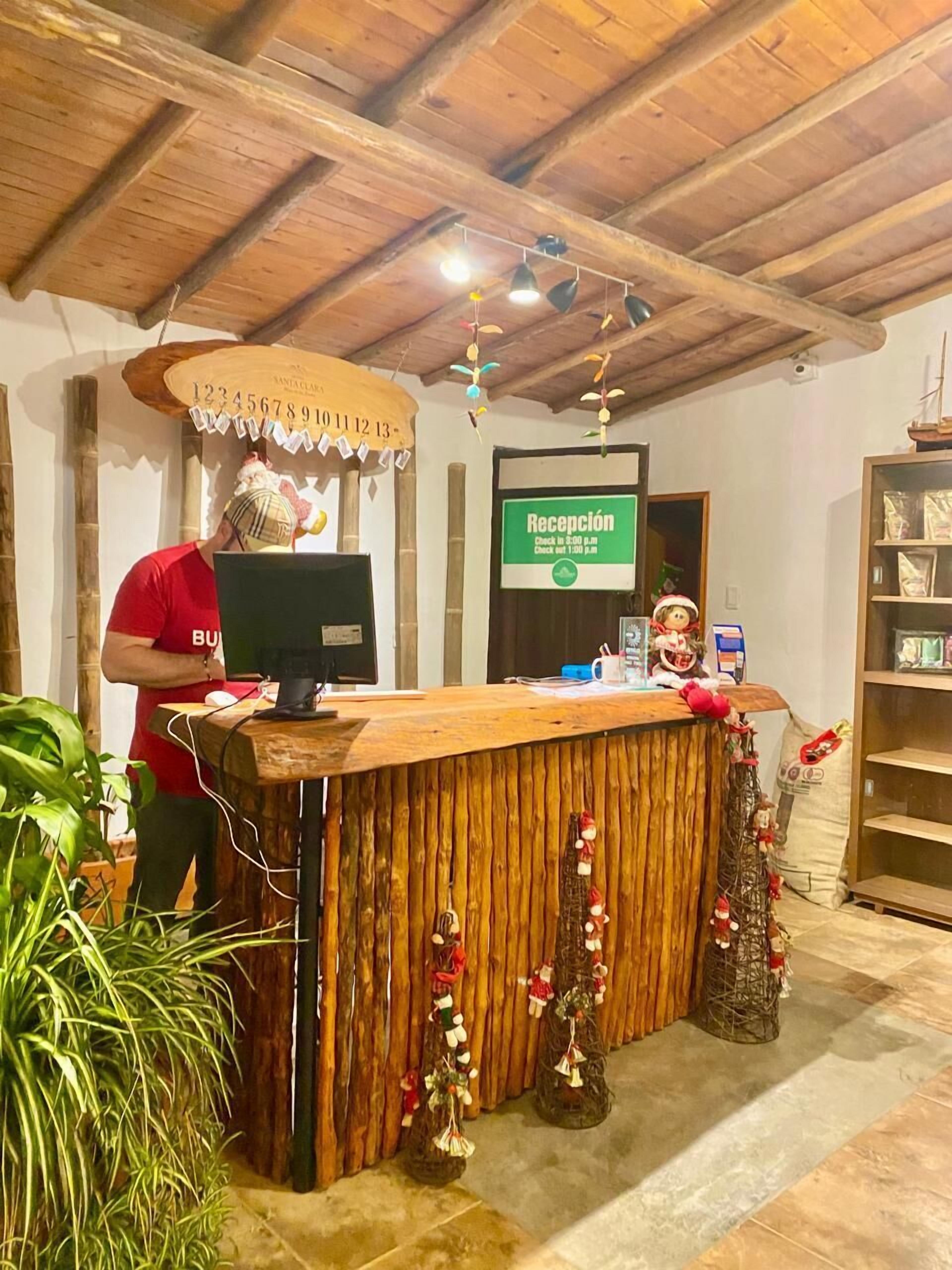 A reception desk with a wooden counter, a computer, and a sign indicating reception hours.