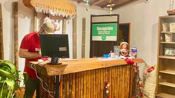 A reception desk with a wooden counter, a computer, and a sign indicating reception hours.