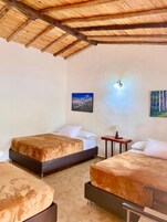 Una habitación con dos camas, una mesita pequeña y una lámpara fijada a la pared.