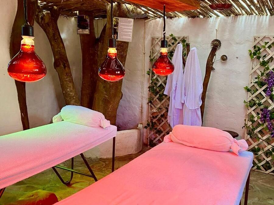 Ett spa-rum med två massagebänkar, röda hänglampor och ett träpanelat tak.