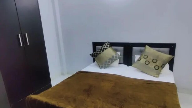 A bedroom with a bed, a wardrobe, and a ceiling light. - Hotel Downtown  (Meerut)