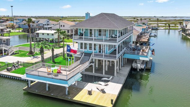 A waterfront property with a multi-level dock, outdoor seating, and a flag. - Dreams Float, Private Heated Pool/Hot Tub, Pier (Jamaica Beach)