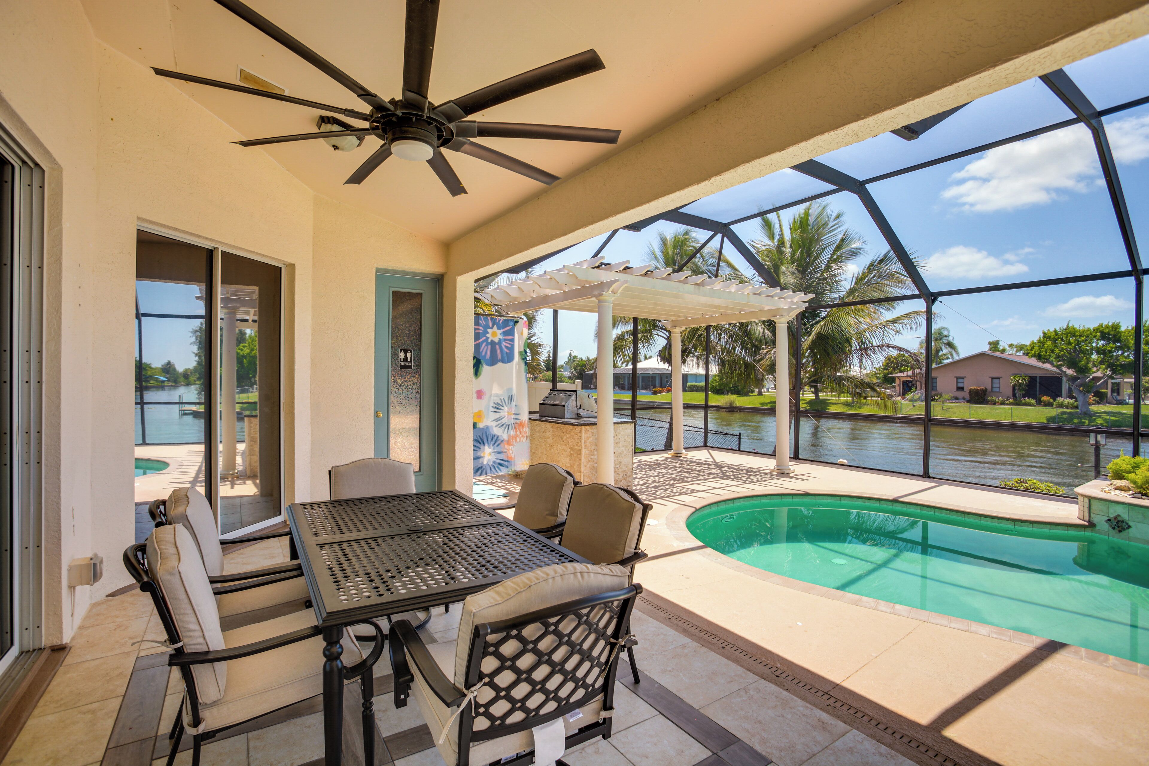 A covered patio area with a pool, outdoor seating, and a view of a residential neighborhood.