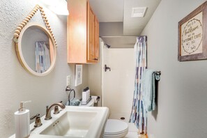 A bathroom with a wooden vanity, a round mirror, a sink, a toilet, and a shower curtain. - Quiet Cabin Retreat: Minutes from Cloudcroft! (Cloudcroft)