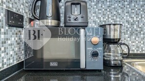 Une cuisine équipée d’une machine à café, d’une bouilloire et d’un four à micro-ondes.