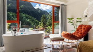 A modern bathroom with a freestanding bathtub, a red upholstered chair, and a large window offering a mountain view. - Huagu Jianzhu Guesthouse Zhangjiajie (Zhangjiajie)