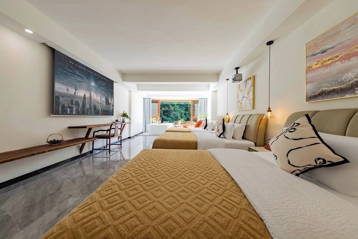 Quarto de hotel moderno com uma cama grande, um sofá, uma escrivaninha e vista para o exterior.
