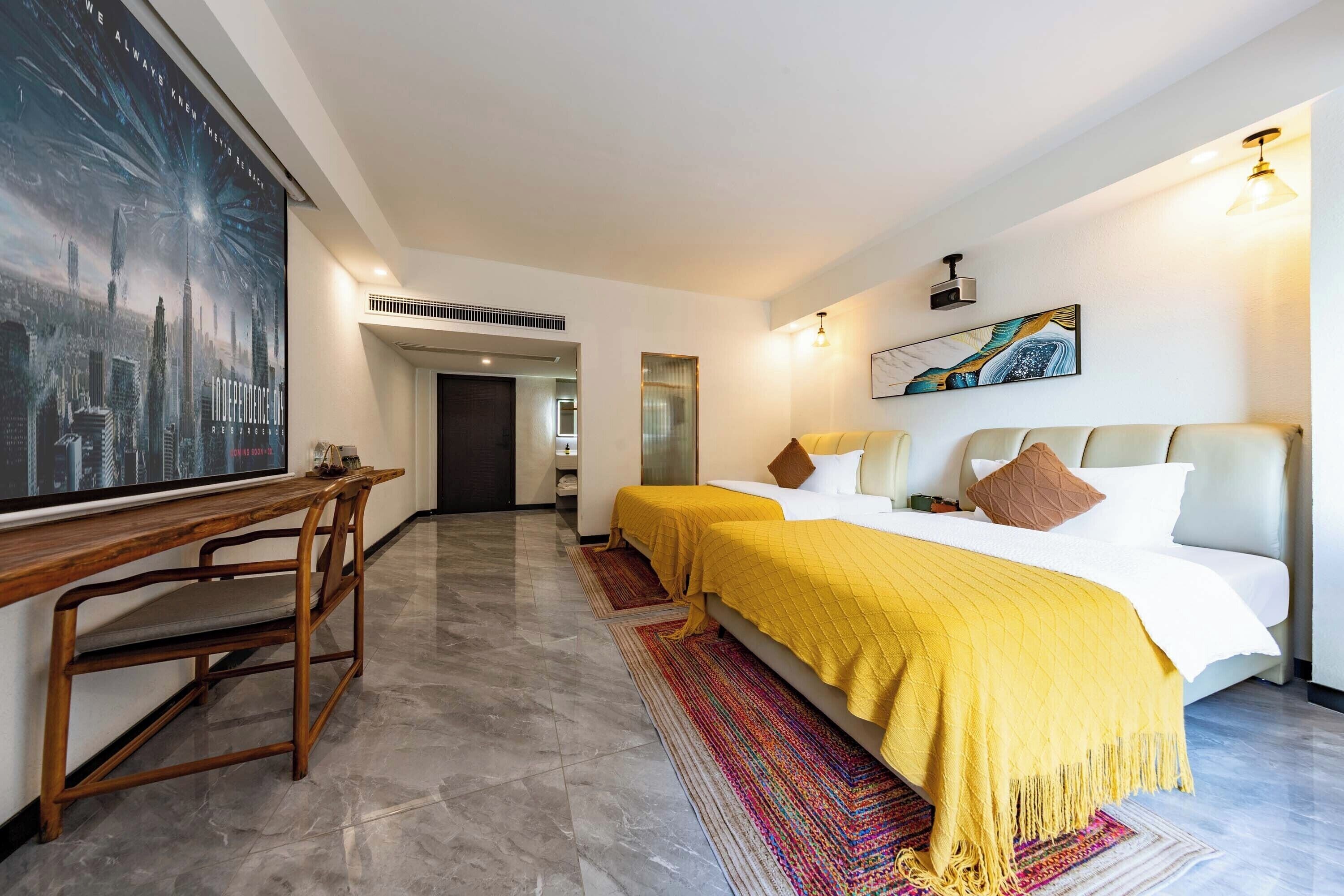 A hotel room with a bed, two bedside tables, a desk, and a large poster on the wall.