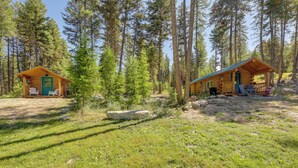 Two log cabins in a forest with outdoor seating and a clear sky. - McGregor Lake Access: Cabin in Wooded Wilderness (Marion)