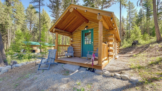 A log cabin with a porch, a green door, and a small deck area with chairs. - McGregor Lake Access: Cabin in Wooded Wilderness (Marion)