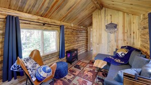 L’intérieur d’une cabane en rondins, avec un canapé, un fauteuil, un petit radiateur et une pancarte sur laquelle on peut lire : « Bienvenue aux Bobcats à Paris, Montana State ».