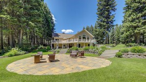 Une grande maison dotée d’un patio et de mobilier d’extérieur, entourée d’une forêt.