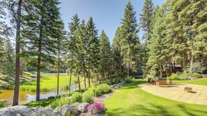 Un jardin aménagé avec une terrasse, un bassin et de grands arbres.