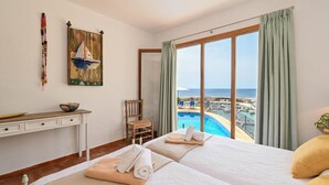 A hotel room with two beds, a desk, a chair, a painting, and a view of a marina and pool. - Casa Timeris - Calpe, Costa Blanca (Calpe)
