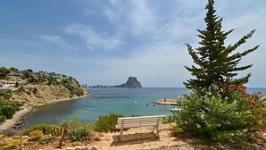 A coastal landscape with a rocky outcrop, a bench, and a tree with pink flowers. - Casa Timeris - Calpe, Costa Blanca (Calpe)
