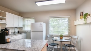 A modern kitchen with white cabinets, a granite countertop, a built-in refrigerator, and a dining area with a round table and chairs. - The Vulcan Octoplex - 8 Private Units/WiFi/Parking (Birmingham)