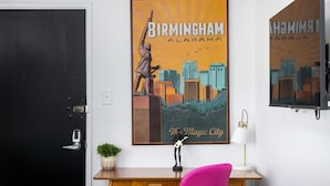 A room with a black door, a desk with a lamp, a chair, and a poster of Birmingham, Alabama. - The Vulcan Octoplex - 8 Private Units/WiFi/Parking (Birmingham)