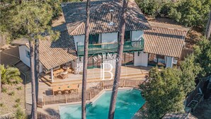 Una casa con piscina, rodeada de árboles y un área de terraza cercada.