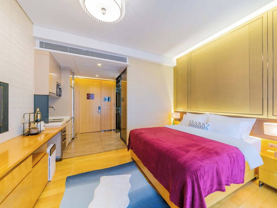 Moderni hotellihuone, jossa on sänky, televisio, työpöytä ja kylpyhuone.