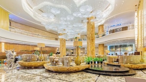 Eine geräumige Lobby mit einem prächtigen Kronleuchter, Marmorböden und mehreren Sitzbereichen.