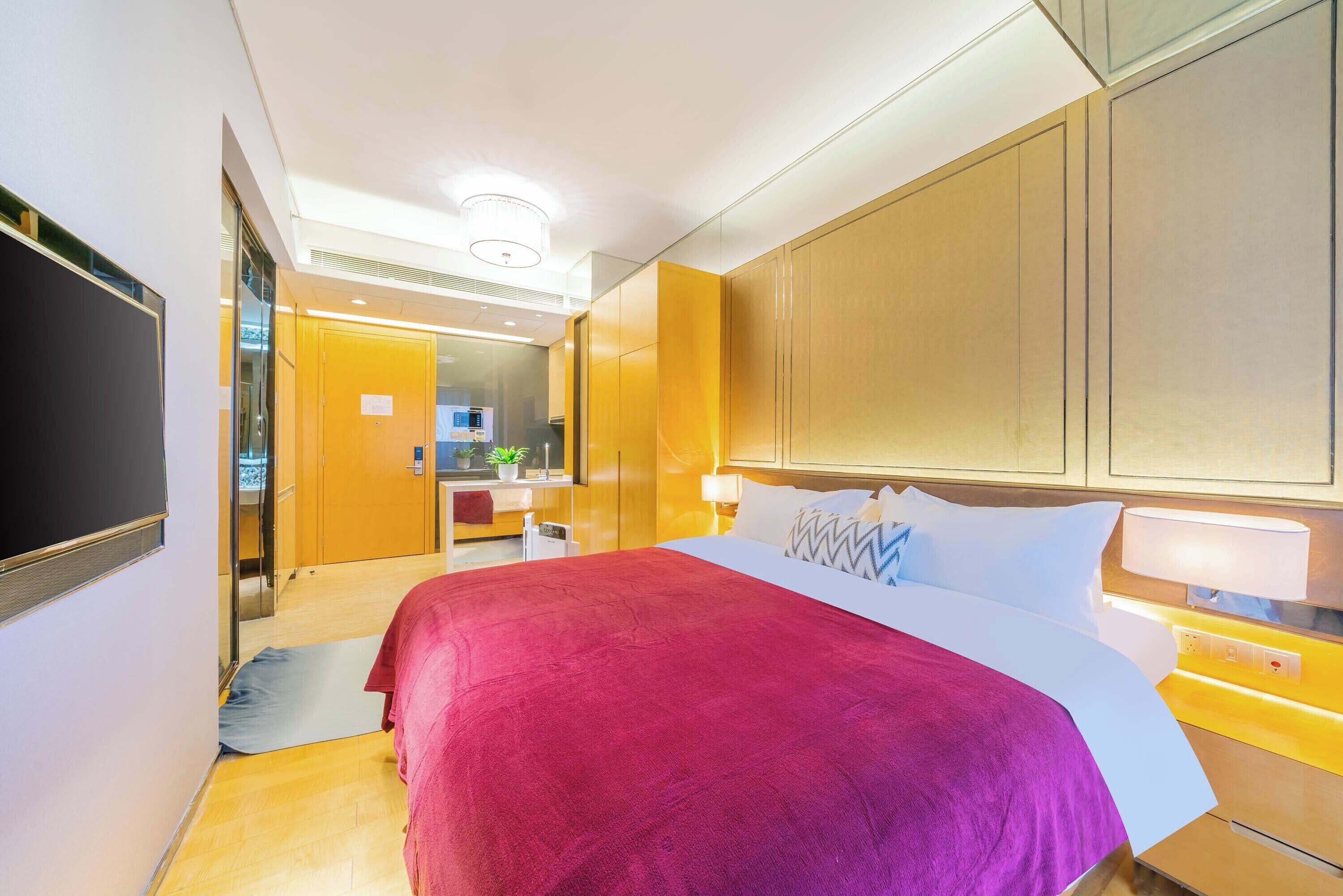 Camera d'albergo con un letto grande, una TV, una scrivania con una sedia e un bagno visibile attraverso una porta aperta.