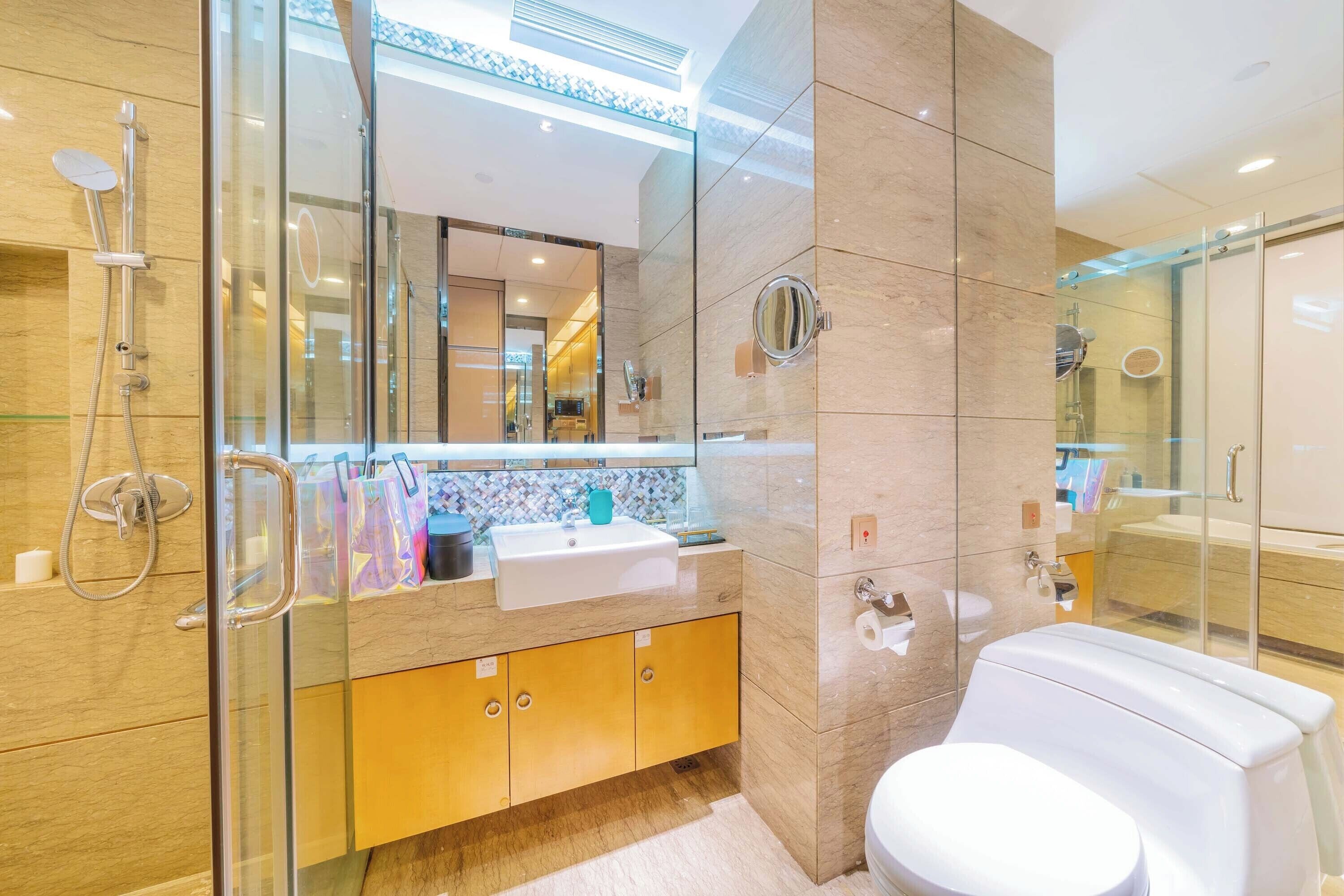 Un baño moderno con cabina de ducha de vidrio, un lavabo blanco y un inodoro.