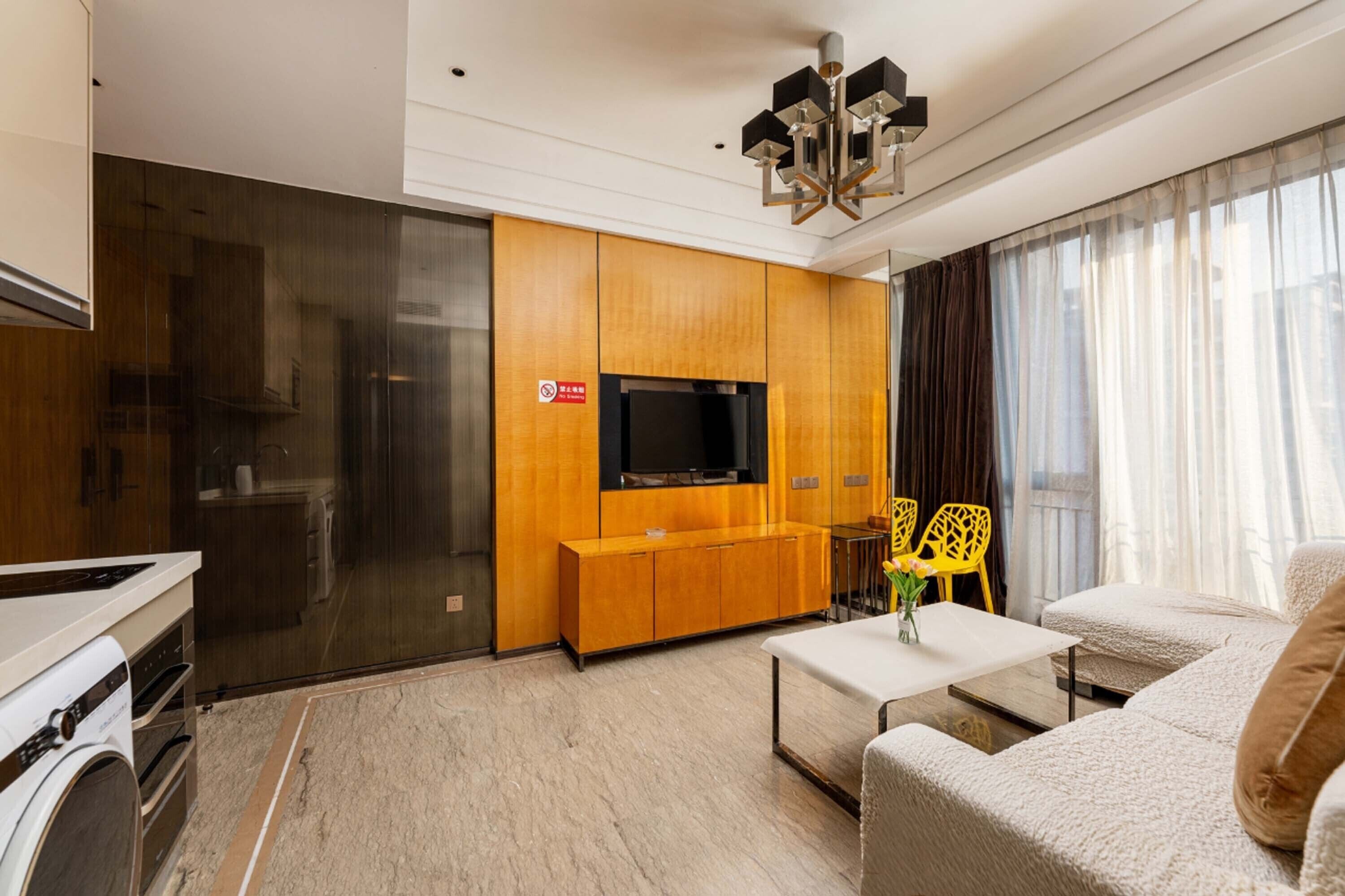 Una sala de estar moderna con un televisor de pantalla plana, armarios de madera, un sofá y una mesa de centro.