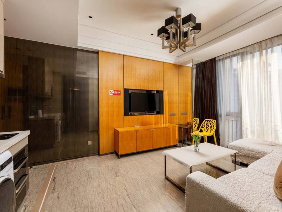 Una sala de estar moderna con un televisor de pantalla plana, armarios de madera, un sofá y una mesa de centro.