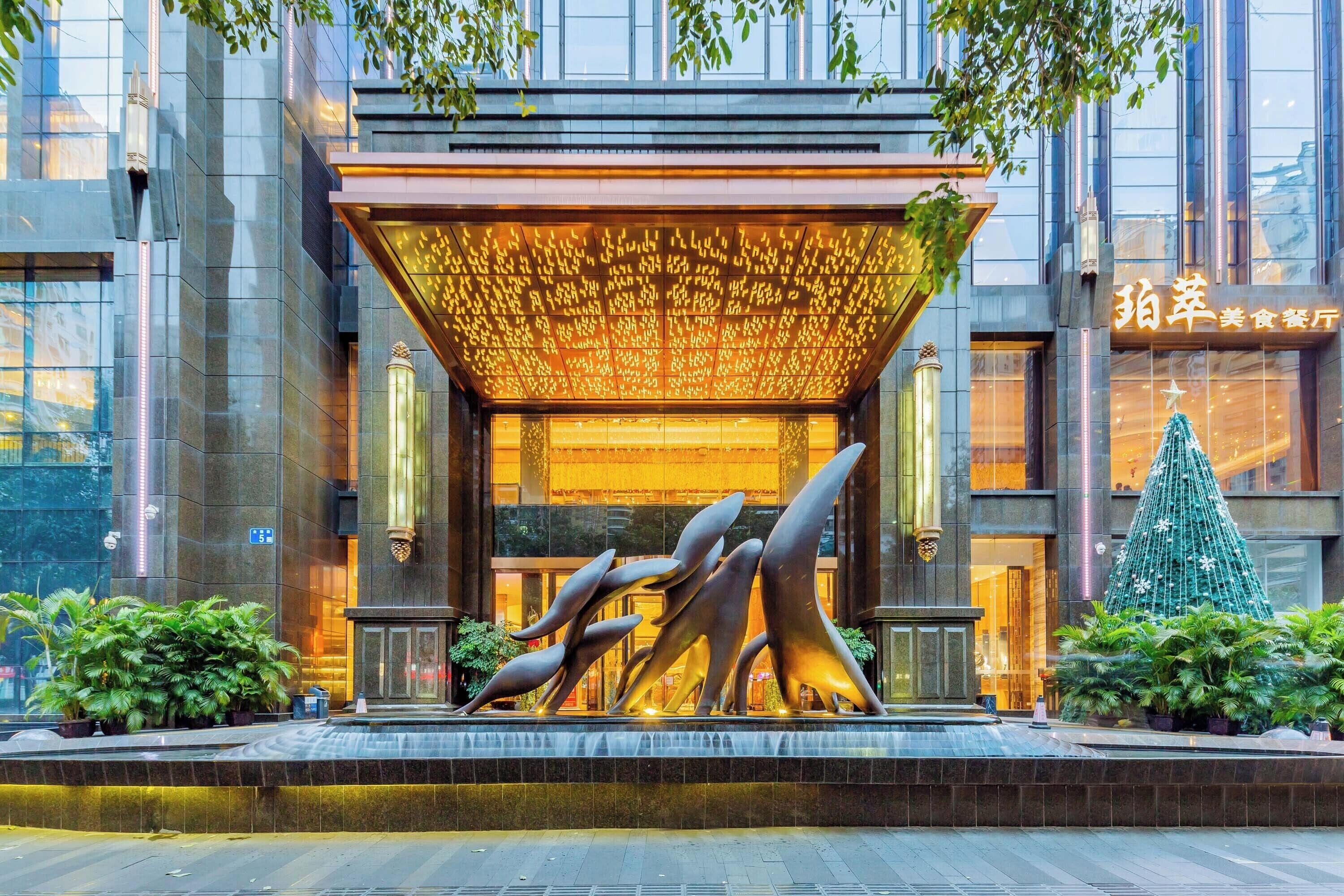A modern building entrance with a unique sculpture, a covered entrance area, and a Christmas tree.