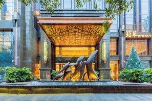 A modern building entrance with a unique sculpture, a covered entrance area, and a Christmas tree. - VanHao Serviced Apartment-Zhujiang Newtown (Guangzhou)