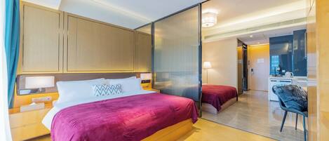 A modern hotel room with a large bed, a desk, and a separate seating area.