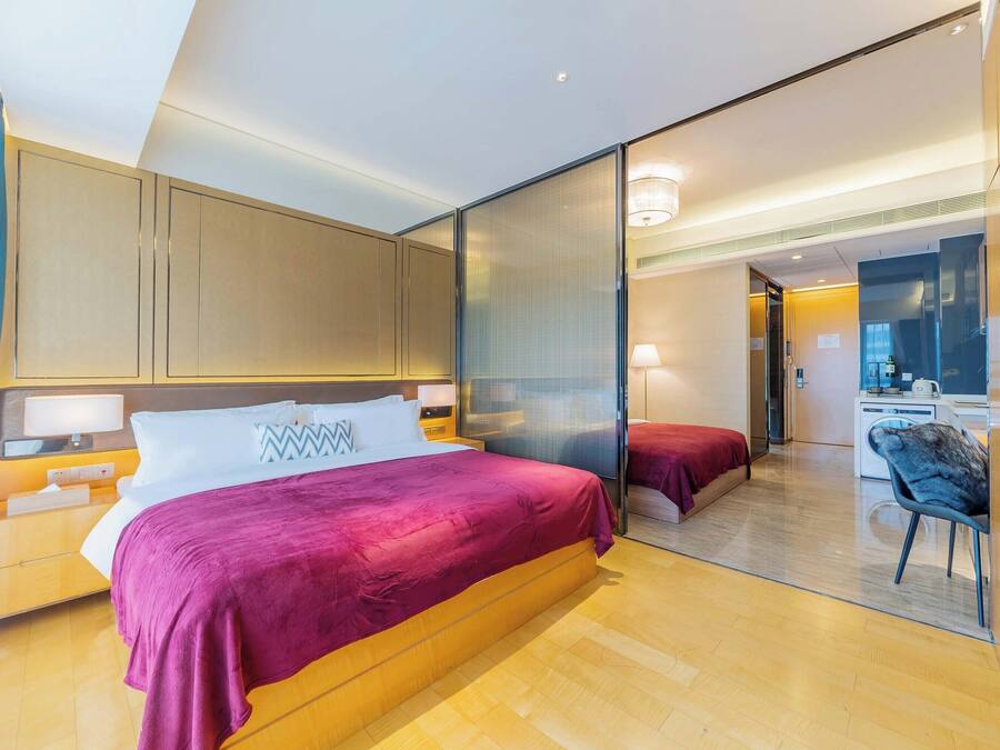 A modern hotel room with a large bed, a desk, and a separate seating area.