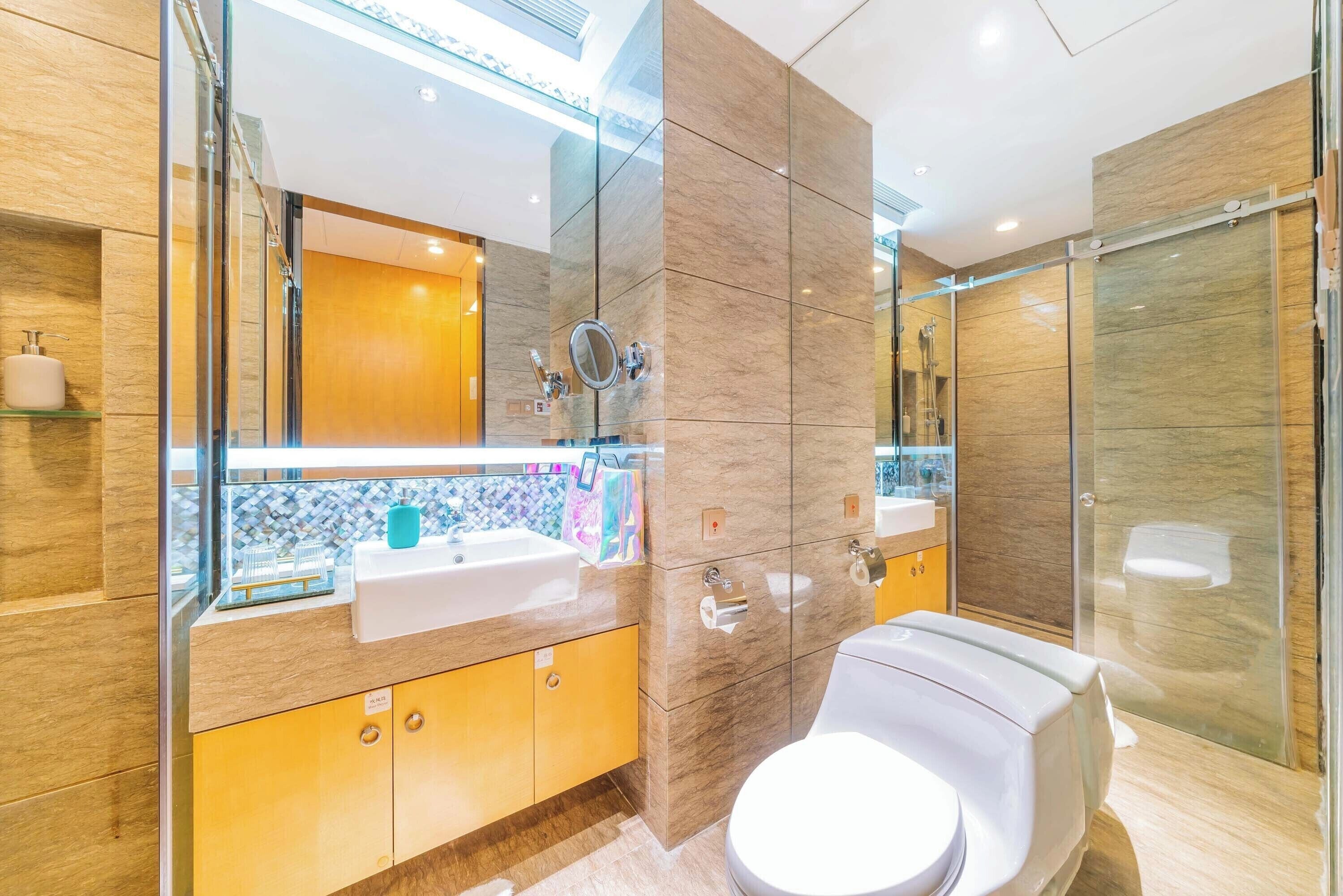 Un baño moderno con cabina de ducha de vidrio, inodoro blanco y tocador con espejo y lavabo.