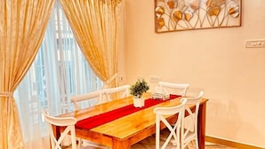 Un espace repas avec une table en bois, des chaises blanches et un chemin de table rouge.