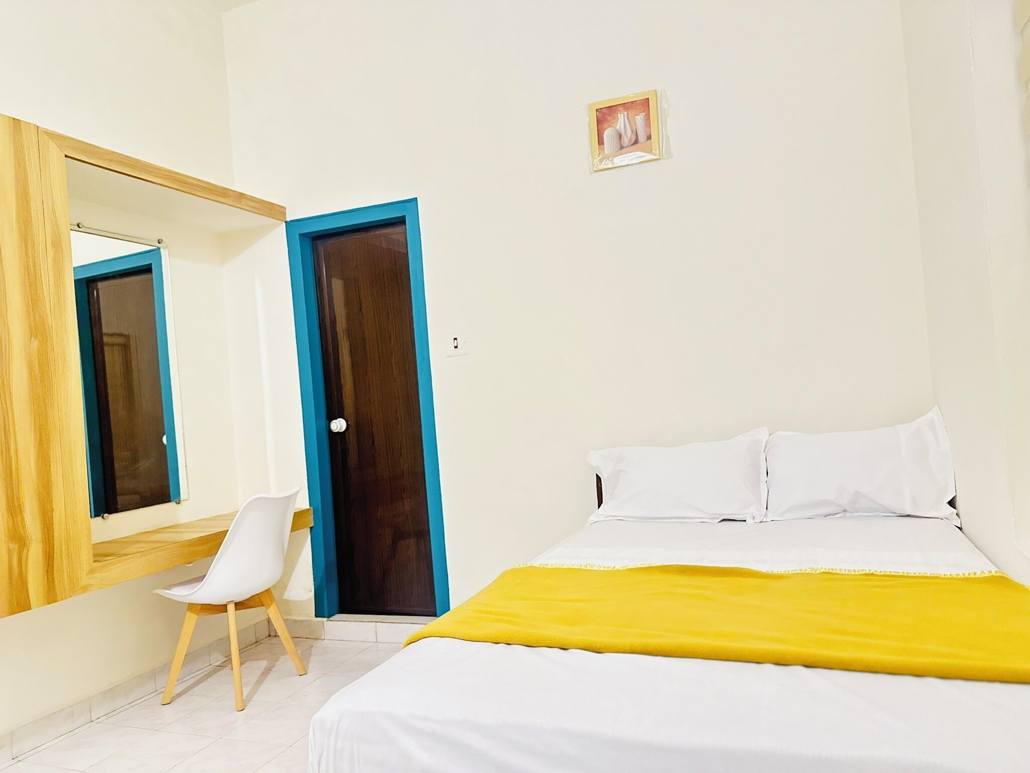 Un dormitorio con cama, una silla, un espejo y una puerta.