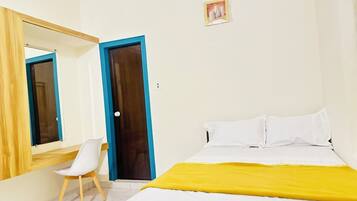 Un dormitorio con cama, una silla, un espejo y una puerta.