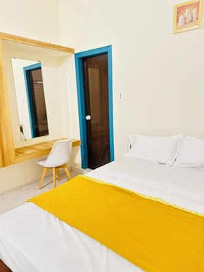 Una habitación de hotel con una cama, una silla, un escritorio y un espejo.