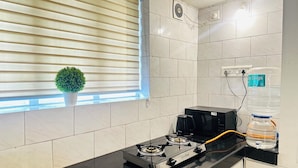 Une cuisine équipée d’une cuisinière à gaz, d’une machine à café, d’un distributeur d’eau et d’une plante en pot.