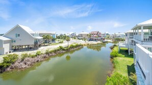 Un quartier résidentiel situé sur la côte, avec des maisons construites le long d’un cours d’eau, dotées de balcons et offrant une vue sur un ciel dégagé.