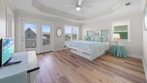 Une chambre avec un lit, un bureau, un ventilateur de plafond et une vue sur l’extérieur.