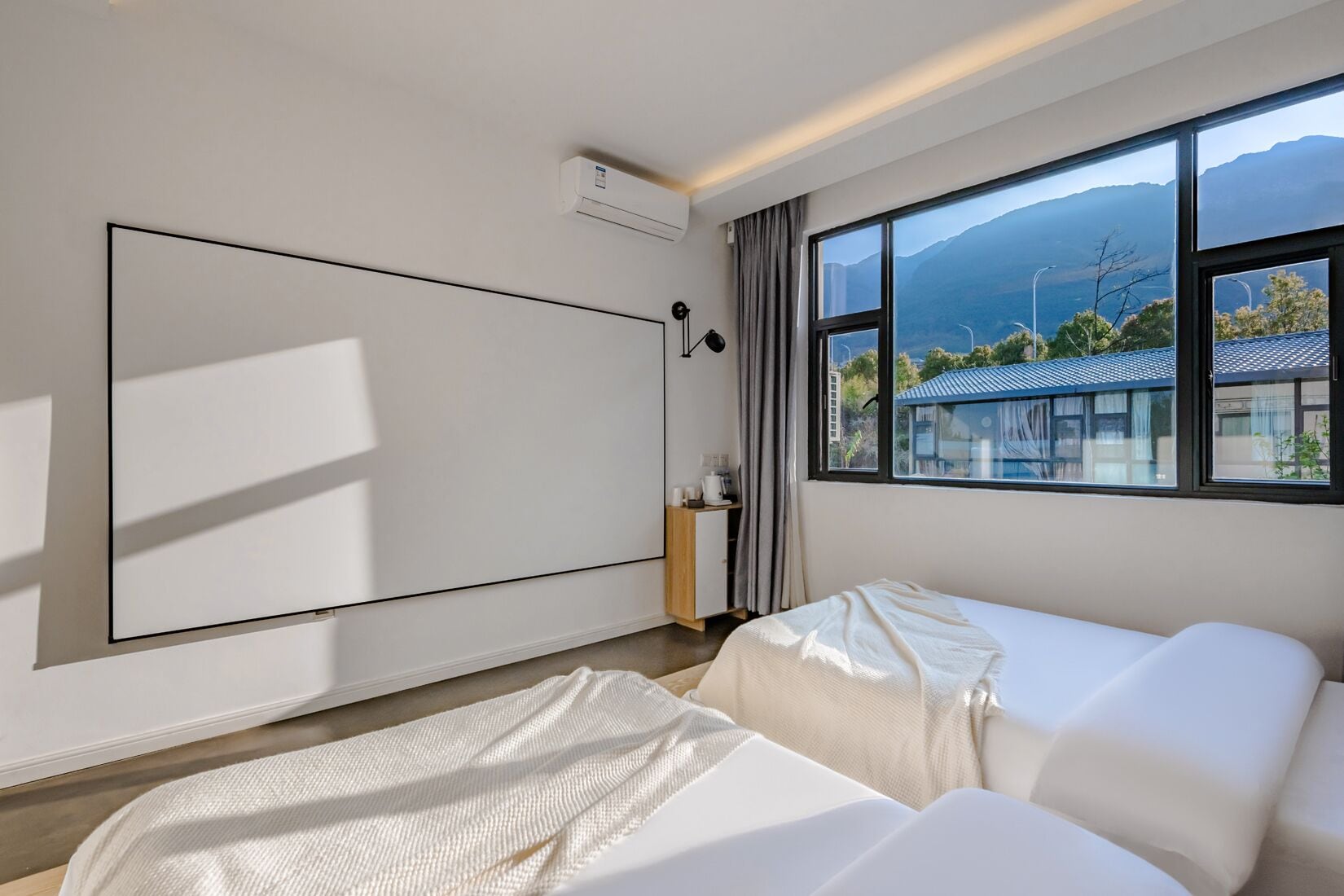Ein modernes Hotelzimmer mit einem großen Bett, einem flachbildfernseher an der Wand, einem Schreibtisch mit Stuhl und einem Fenster mit Blick auf die Berge.