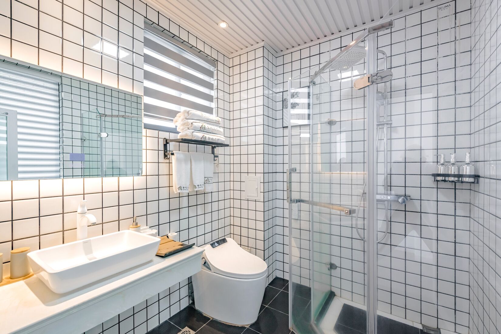A modern bathroom with a white sink, toilet, and glass-enclosed shower.