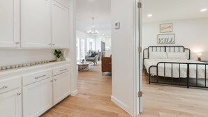A modern bedroom with a bed, bedside table, and a view of the living area. - The Abbey at Lake Hefner (The Village)
