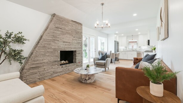 A modern living room with a stone fireplace, a round marble coffee table, and a comfortable seating area. - The Abbey at Lake Hefner (The Village)