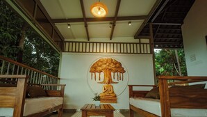 A room with wooden furniture, a Buddha statue, and a ceiling light.