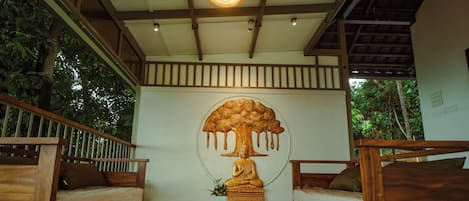 A room with wooden furniture, a Buddha statue, and a ceiling light.
