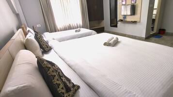 A hotel room with two beds, a wardrobe, a TV, and a mirror.