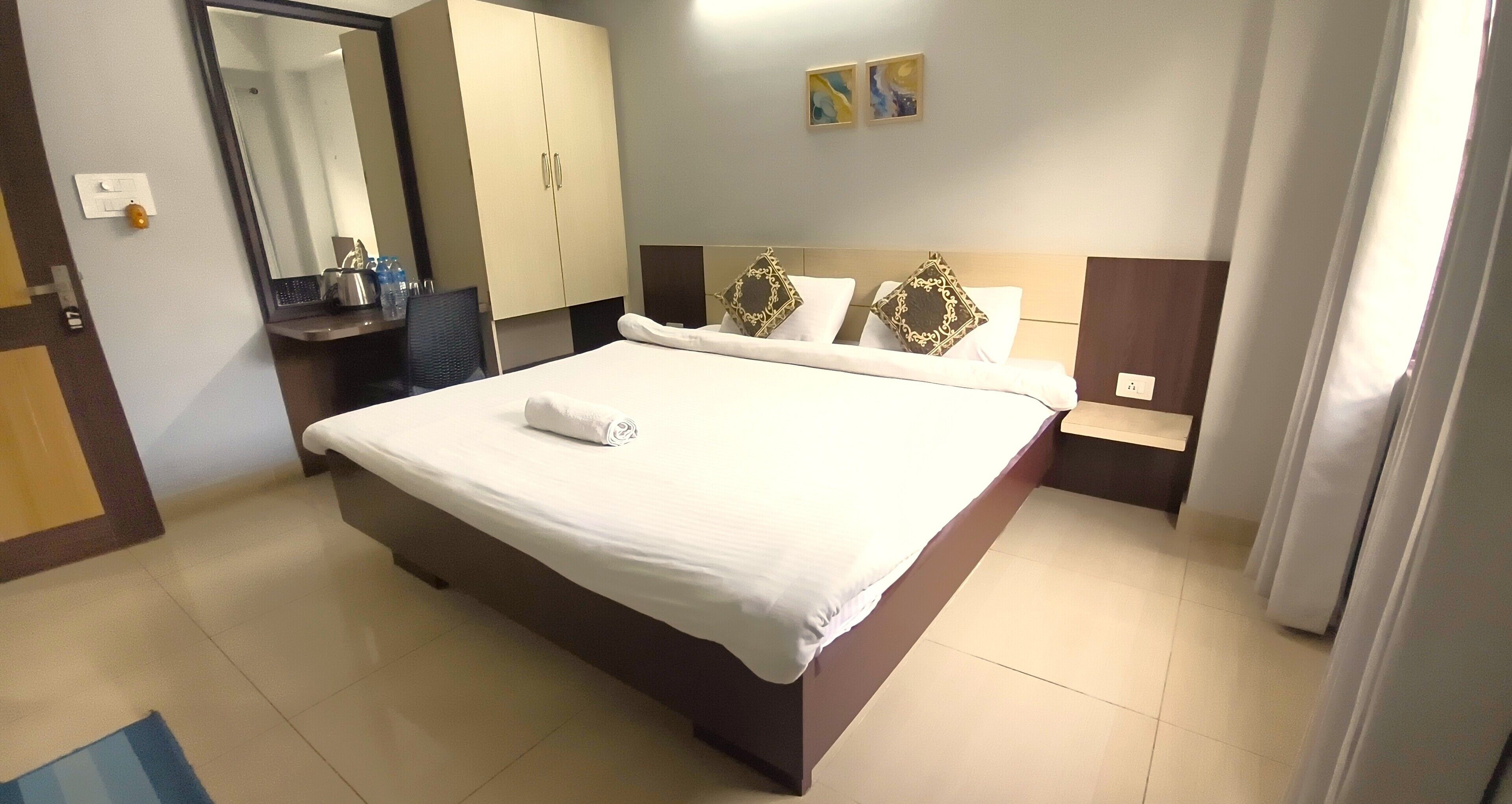 Habitación de hotel con cama, espejo, armario y una mesita de noche con artículos de aseo.