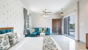 Una habitación de hotel moderna con una cama grande, un sofá color turquesa y un balcón con vistas.