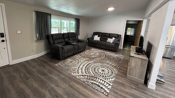 Un salon spacieux avec un canapé en cuir marron foncé, un fauteuil assorti et un tapis à motifs.